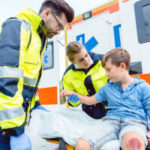 Emergency doctors caring for accident victim boy sitting on stre