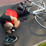 Bicycle accident. Biker lying on the road and holding his head