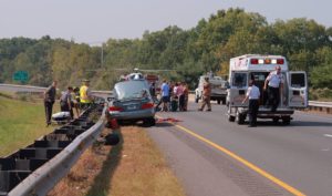 Car crash scene with emergency personnel and passenger in car accident settlement receiving treatment.