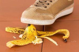 Premises liability: foot in sneaker about to step and slip on banana peel illustrates specific types of liabilities. 