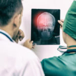 Doctors Looking At X-ray Film Of Patient 's Head