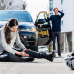 Full length of a young female bicyclist fallen down on street wi