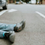 Person lying on the ground after a car accident