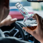 man drinking alcohol behind wheel