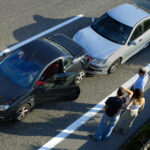 three people on side of road after crash